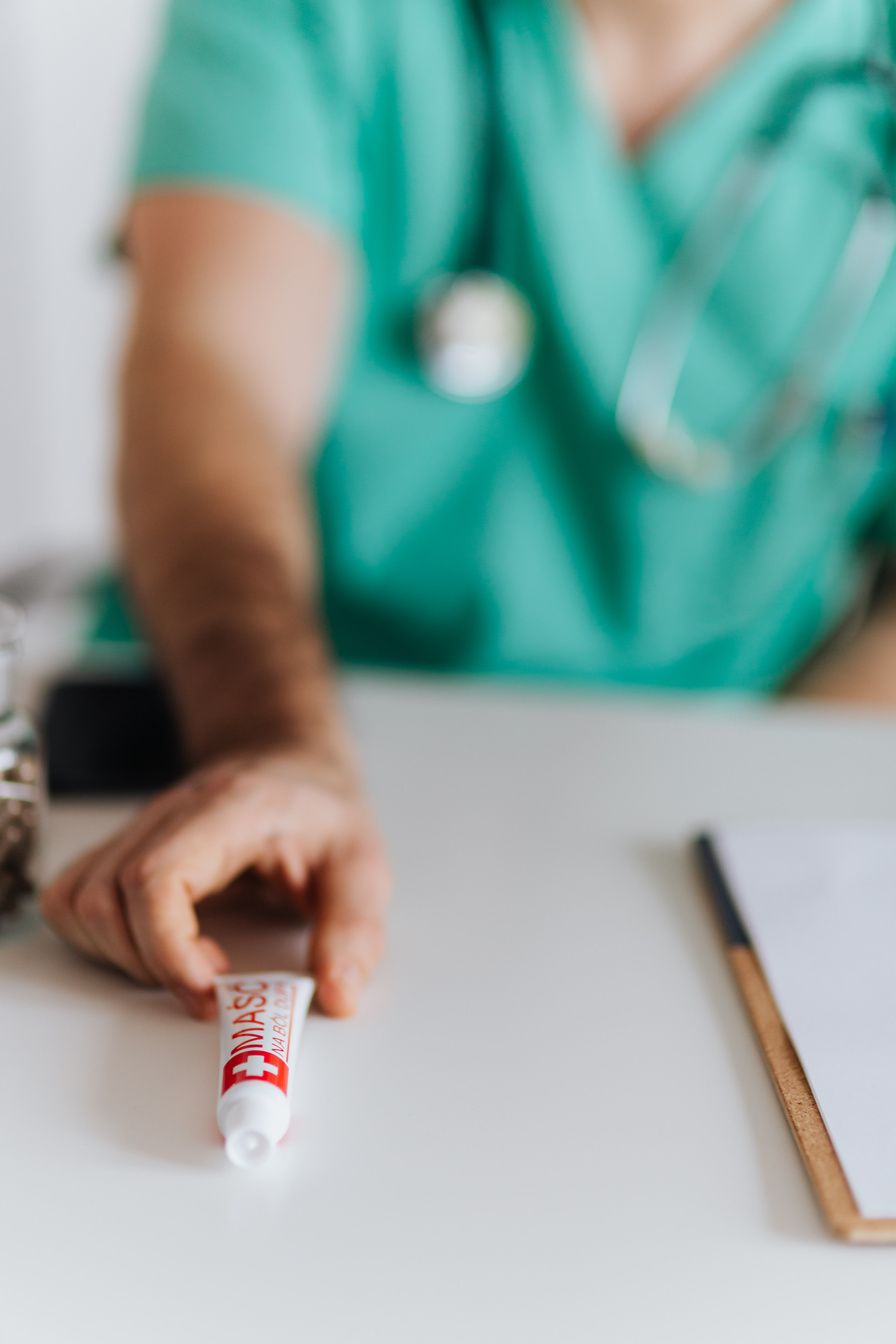 Crop man doctor with stethoscope giving ointment